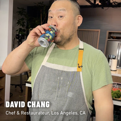 David Chang in a green shirt and grey apron sipping a can of Aftershift Non-Alcoholic Brew