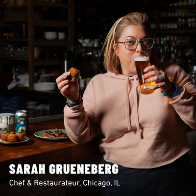 Sarah Gruenberg sipping a glass of non-alcoholic brew sitting at a bar next to food