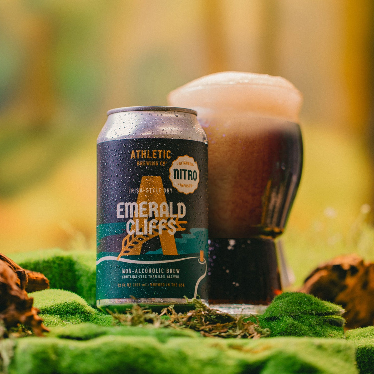 Nitro Emerald Cliffs can and glass on a mossy surface.
