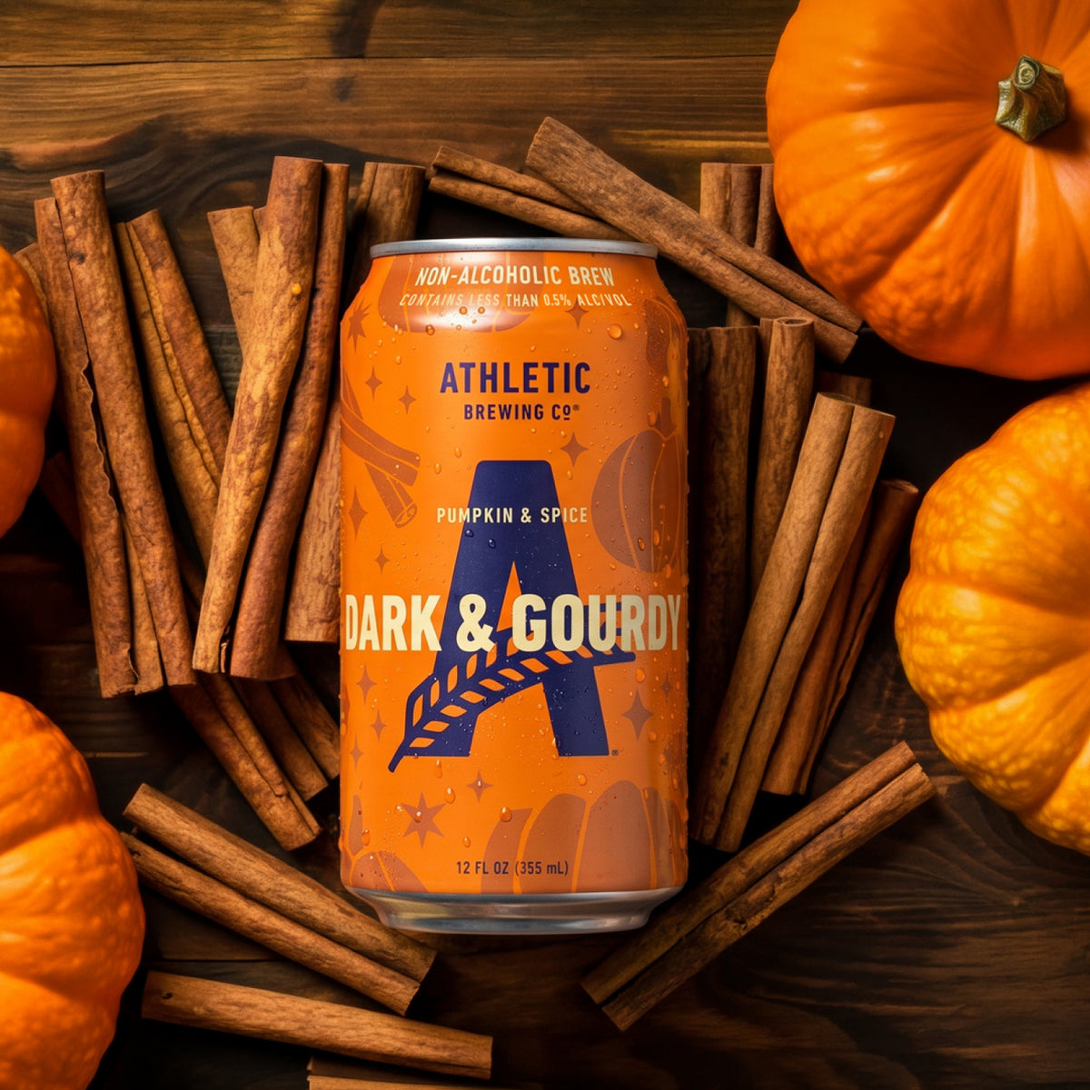 Athletic Brewing Dark & Gourdy Pumpkin & Spice non-alcoholic brew can surrounded by pumpkins and cinnamon sticks.